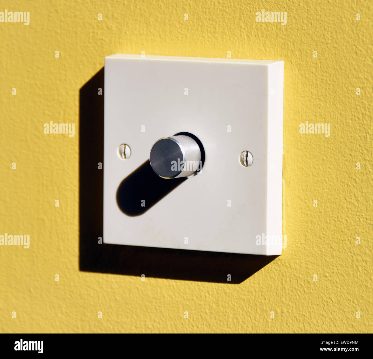 Electric light dimmer switch on yellow wall. Kendal, Cumbria, England, United Kingdom, Europe. Stock Photo