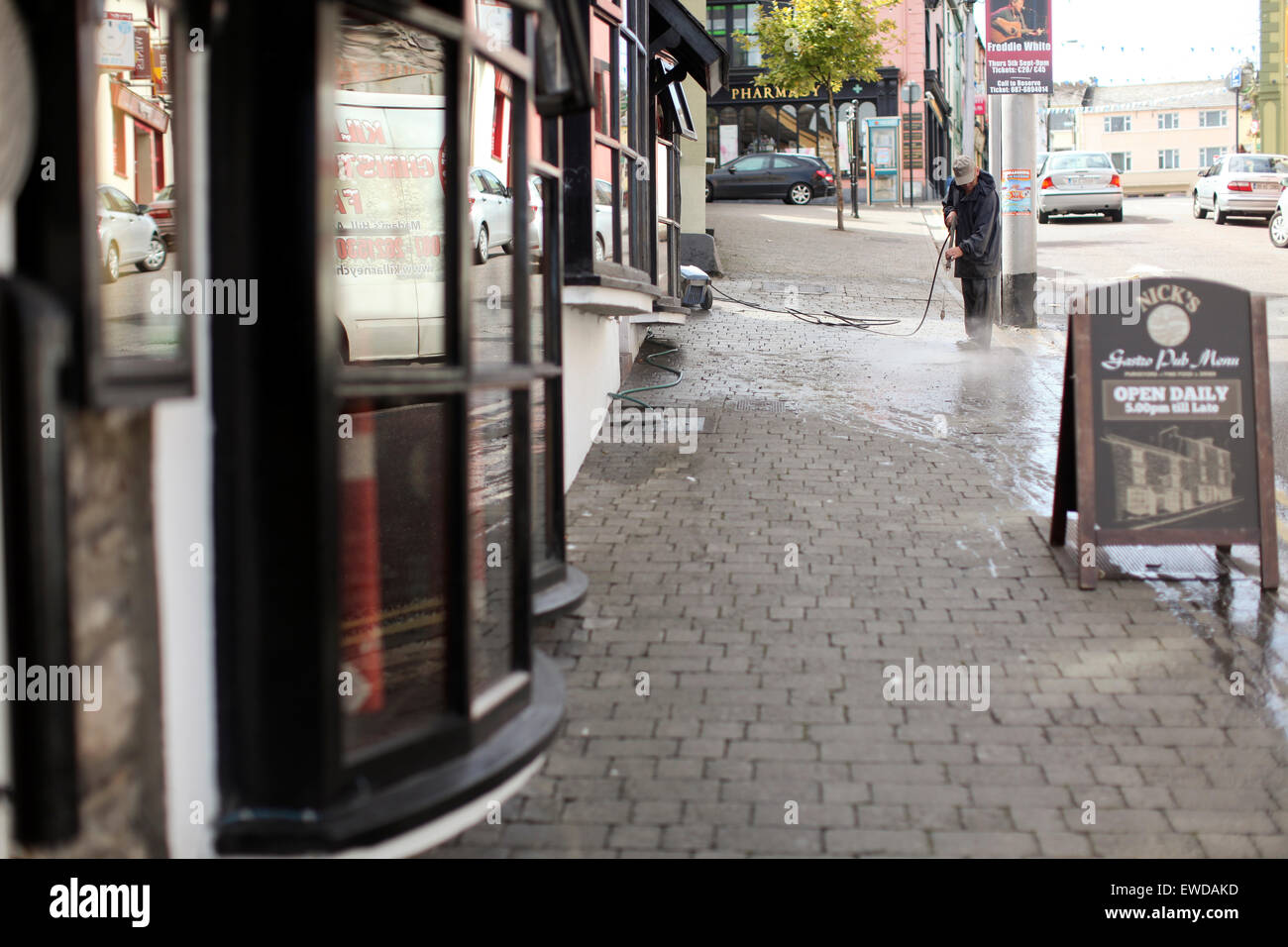 Man cleans the sidewalk in front of a pub in Ireland. Stock Photo