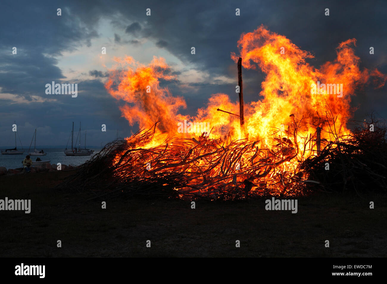 Nivaa Harbour, north of Copenhagen, Denmark. June 23, 2015. St. John's Eve, the Midsummer Eve or Sankthansaften in Denmark is celebrated by lighting bonfires at sunset. A straw and rag witch is placed on top of the bonfire before it is lit and time for the traditional speech and midsummer songs. The bonfire events including a cultural speech by a well-known person and the singing of the traditional midsummer song are held by most local authorities throughout the country. But local bonfires and celebrating parties are arranged nearly everywhere. Credit:  Niels Quist/Alamy Live News Stock Photo