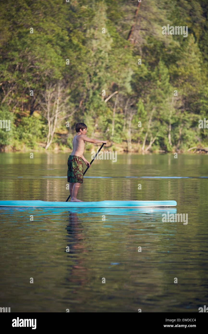 A boy paddling a paddle board on Whiskeytown Reservoir in Northern California on a warm summer day. Stock Photo