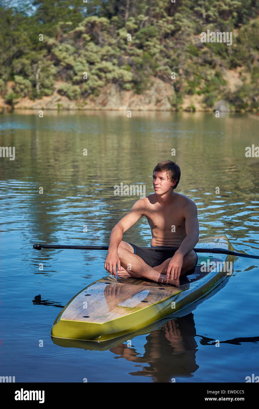 A teenage boy relaxing on a paddle board on a small lake in Northern California. Stock Photo