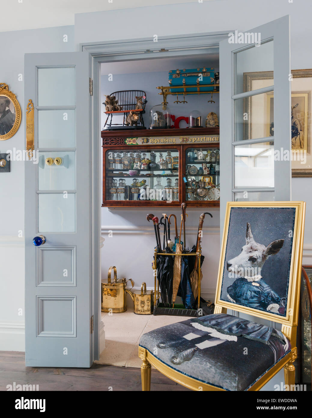 Upholstered Visitorian chair with sheeps head by Cory in entrance hall with umbrella stand and antique wall dresser Stock Photo