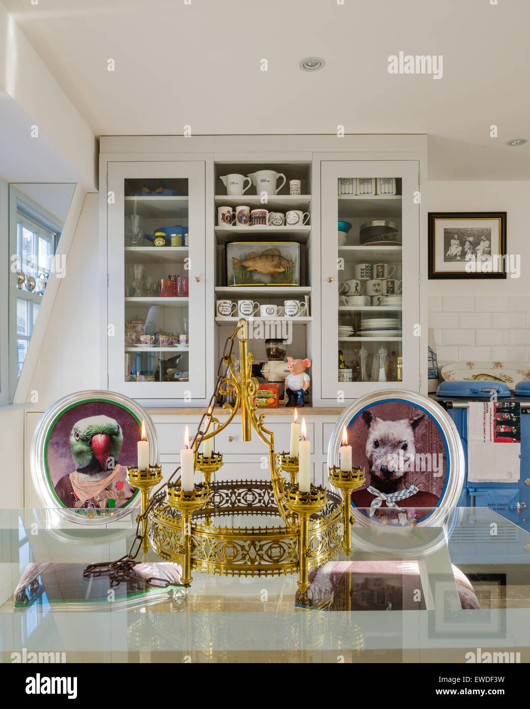 Dining chairs upholstered in Cory's Visitorian prints around glass topped dining table in kitchen with white dresser and aga Stock Photo