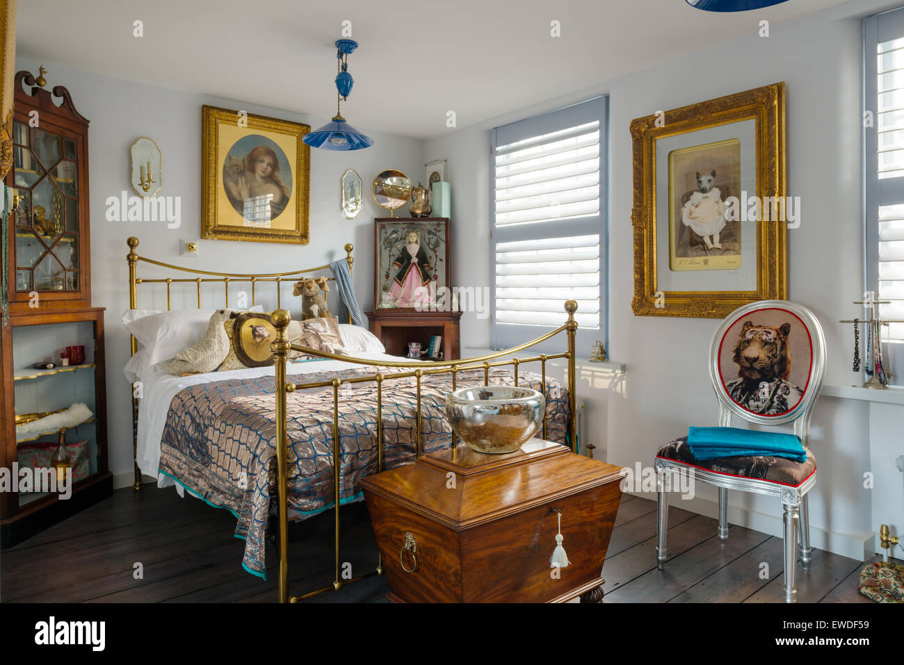 Brass framed bedstead in elegant bedroom with antique wine cooler and Visitorian dining chair Stock Photo