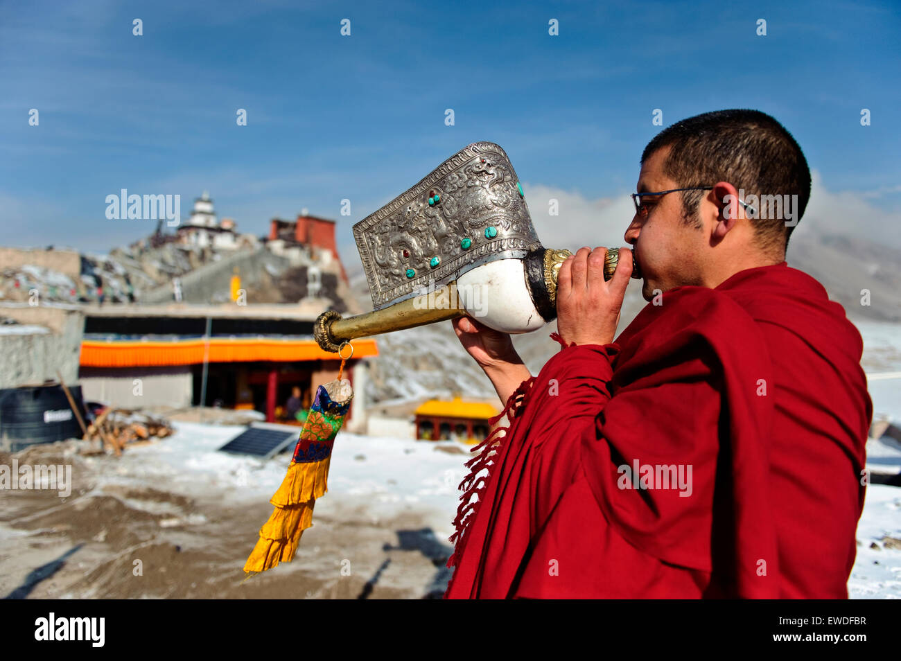 A monk playing Tibetan conch shell horn (dungdkar) on a roof of Spitok Monastery, Ladakh, India. Stock Photo