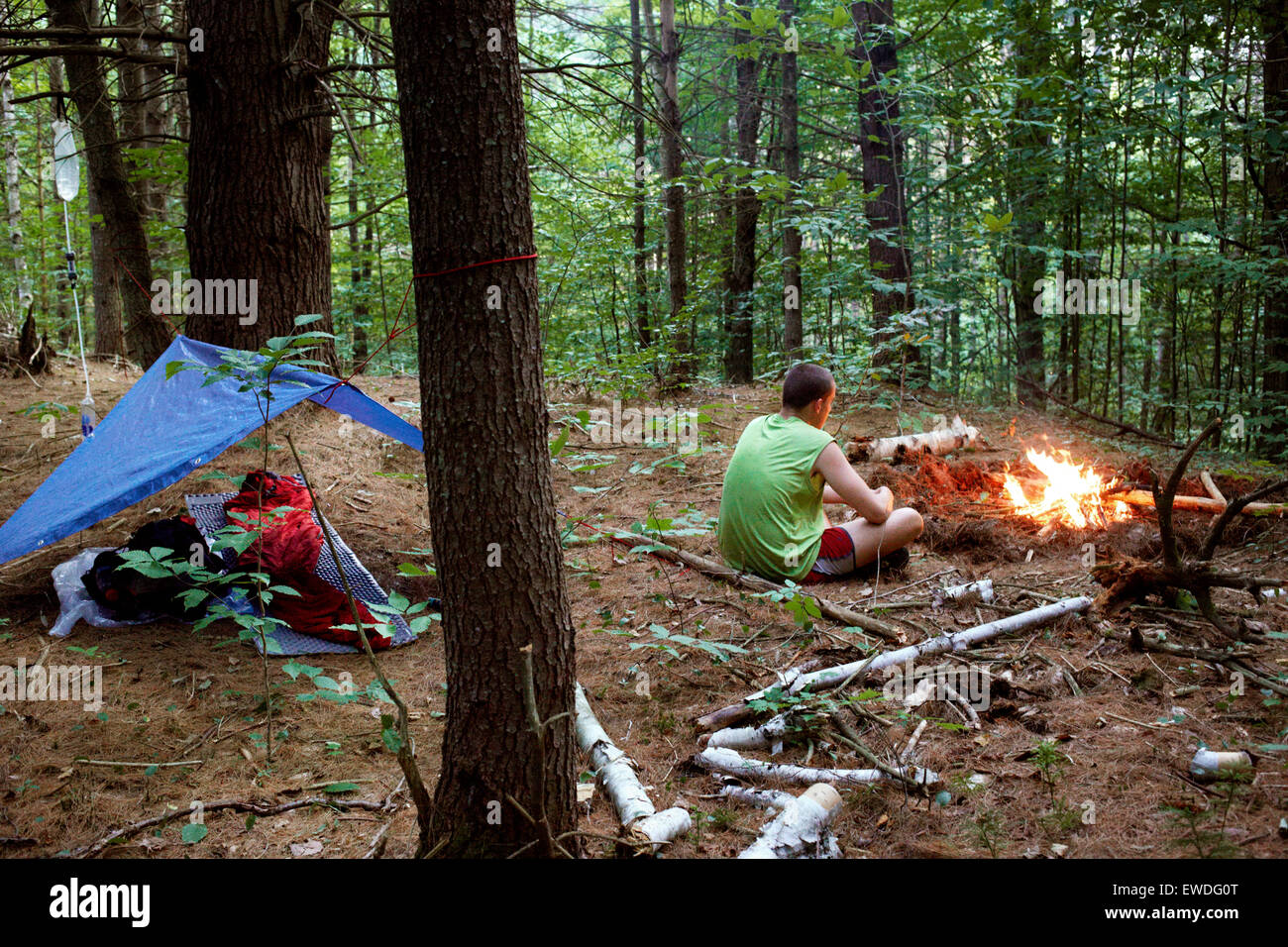 A hiker tends to a small camp fire next to his shelter. Stock Photo