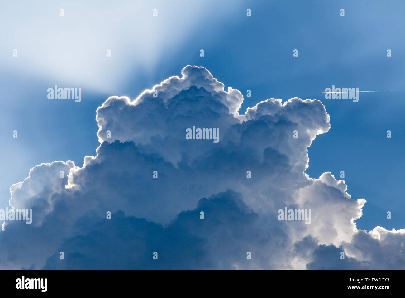 Rapidly building cloud screening the sun with an aircraft in the sky Stock Photo