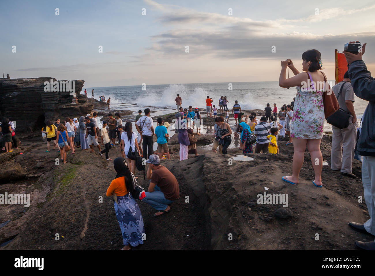 Tourists having leisure time on a rocky beach in Tanah Lot, Tabanan, Bali, Indonesia. Stock Photo