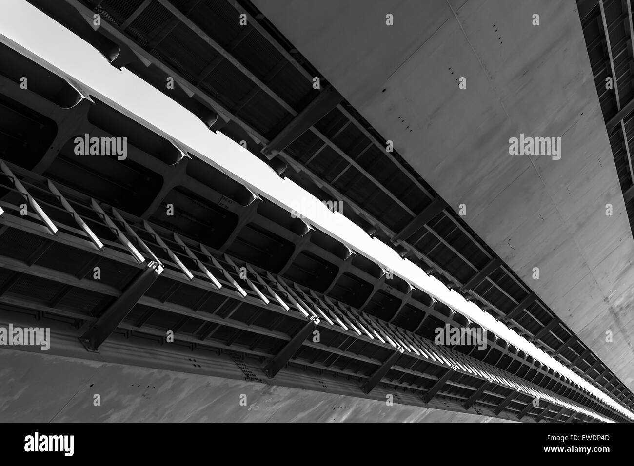 Underneath view and detail of a metal road bridge and sunlight in black and white Stock Photo