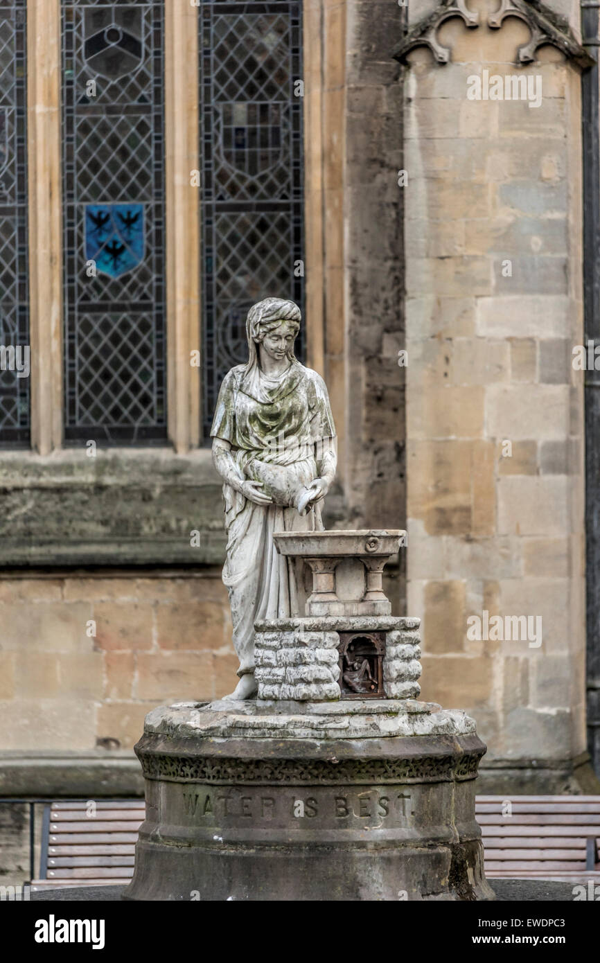 Statue of a woman with a jug of water by a fountain next to Bath Abbey