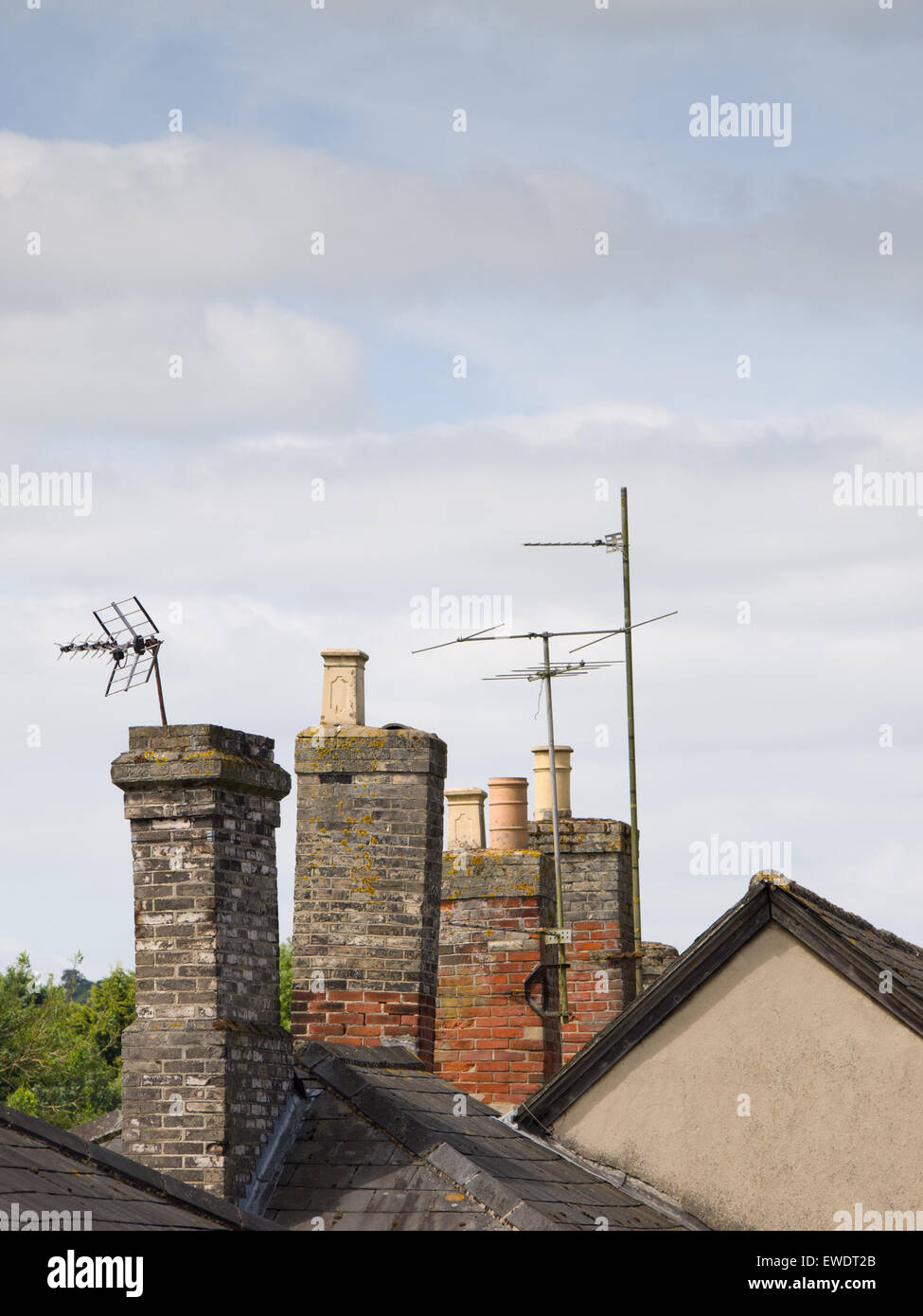 Old brick chimneys and TV aerials point skywards from rooftops. Stock Photo