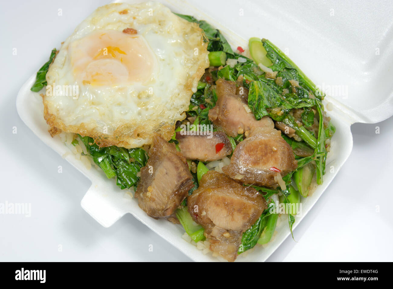 Steamed rice top with stir-fried Kale with crispy pork belly, on top with fried egg Stock Photo