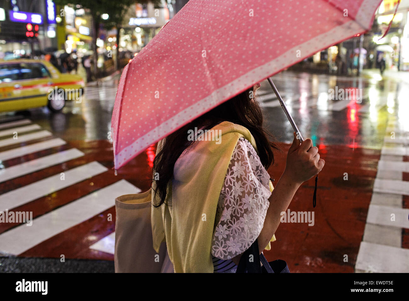 A young woman with umbrella in the rain in Shibuya at night in Tokyo, Japan Stock Photo
