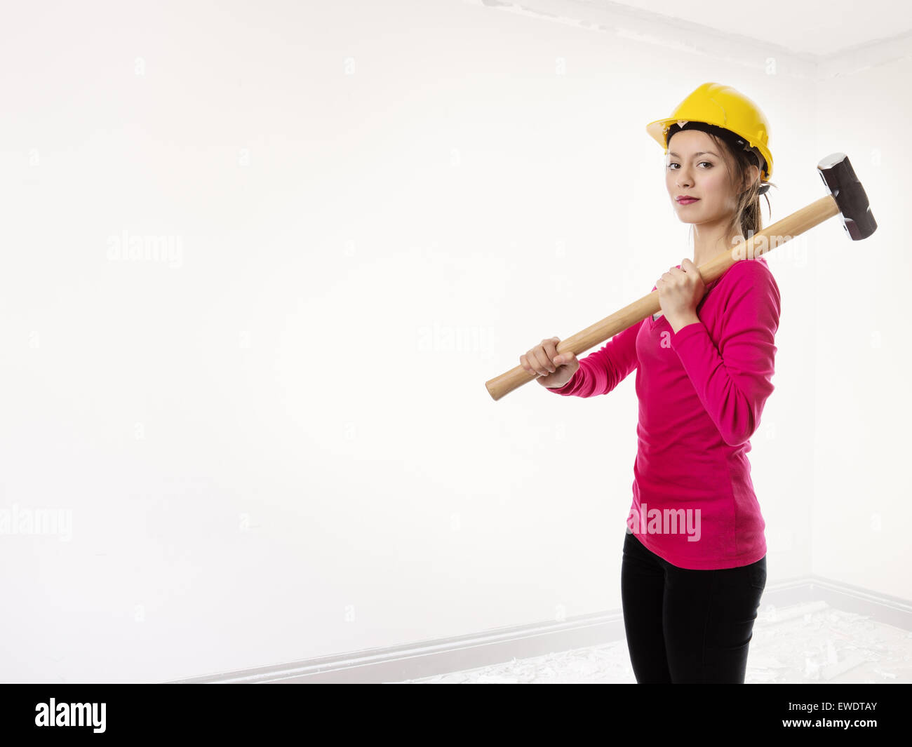 woman holding a sledgehammer and wearing a hard hat about to smash
