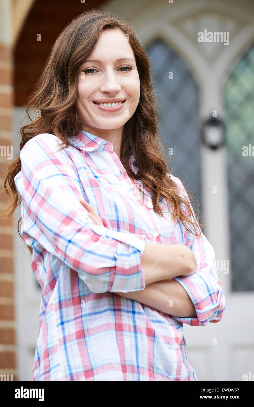 Portrait Of Woman Standing Outside Front Door Of Home Stock Photo