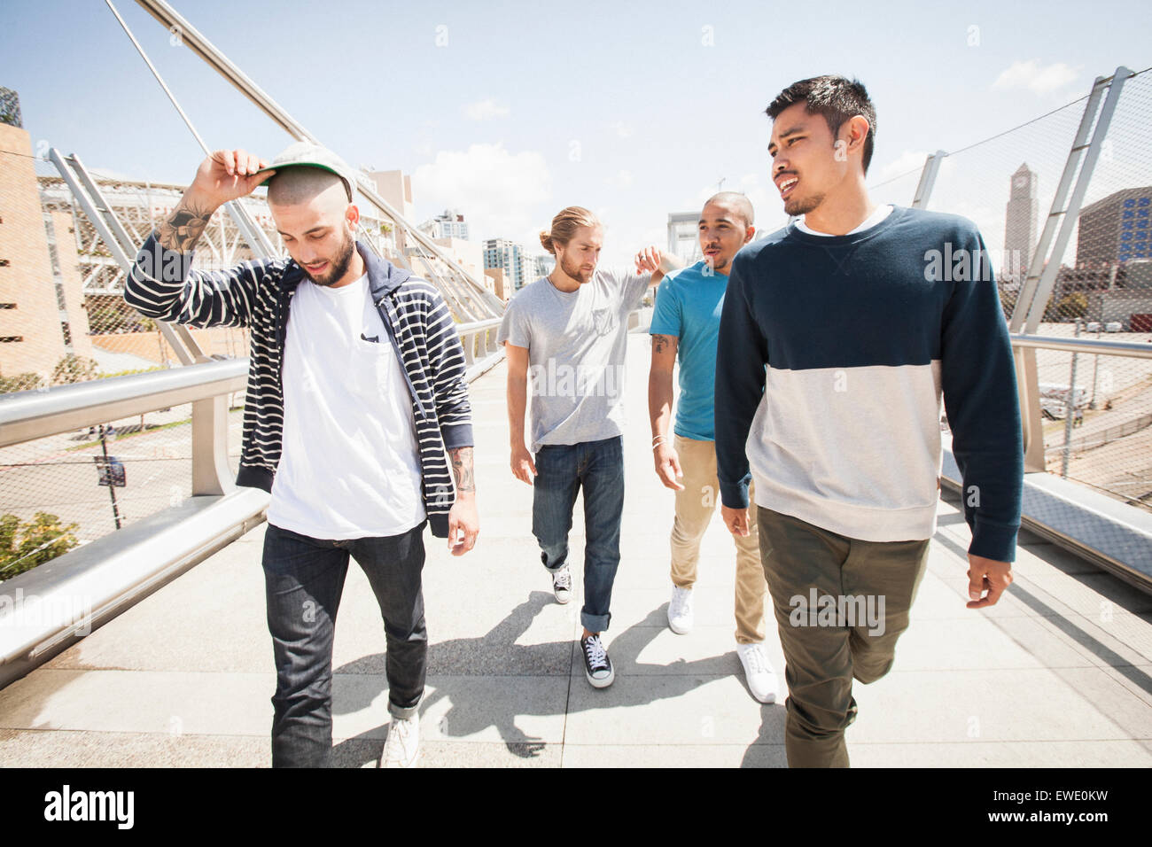 Group of young men walking along footbridge Stock Photo