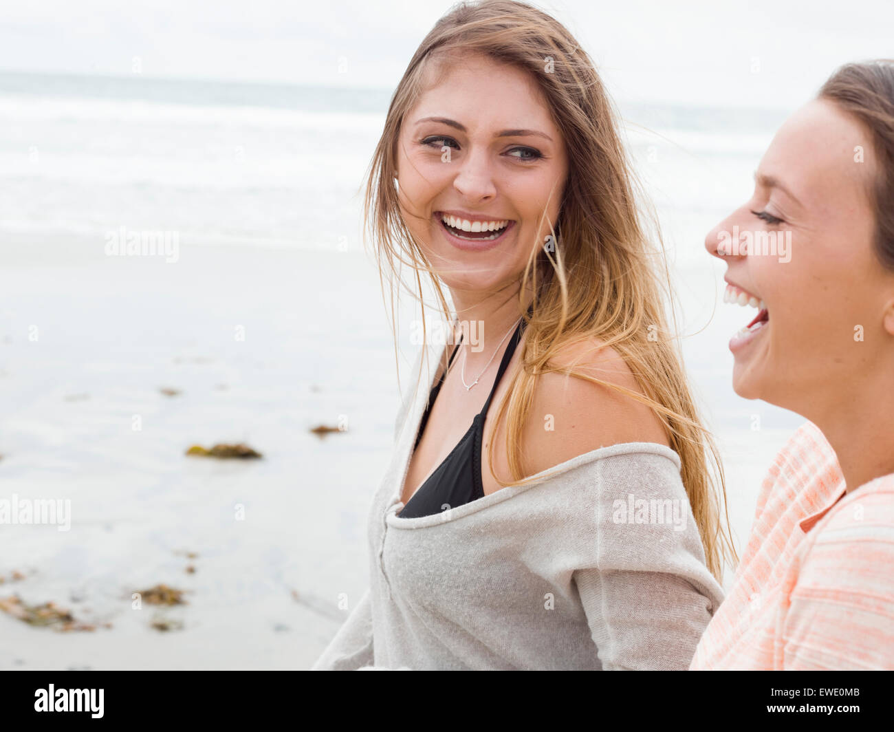 Two smiling young women walking on a beach Stock Photo