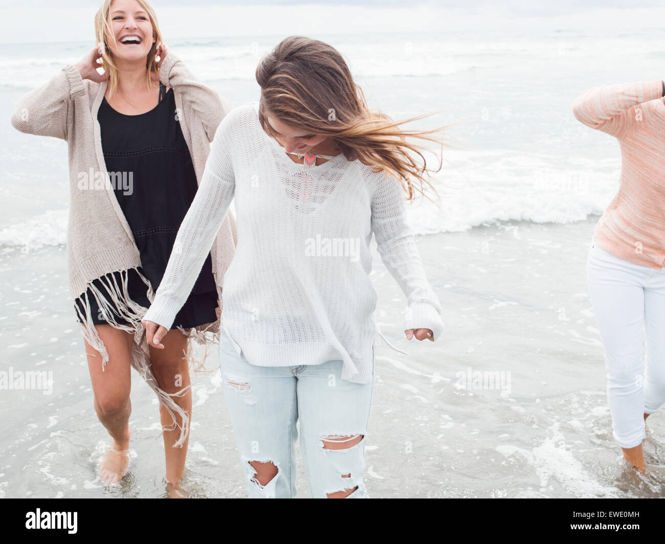 Three smiling young women walking on a beach Stock Photo
