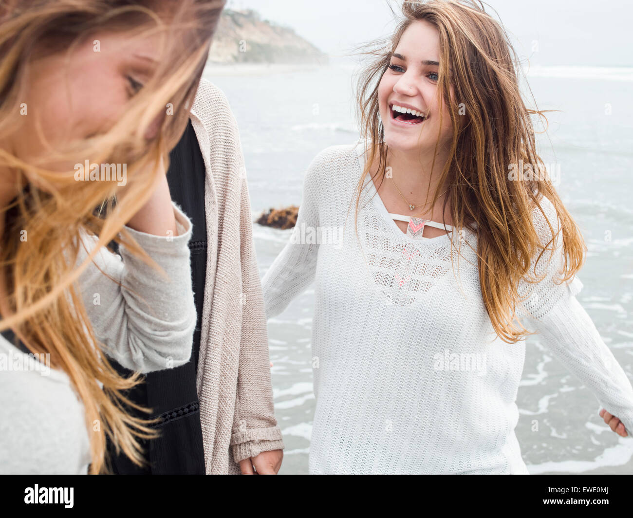 Three smiling young women walking on a beach Stock Photo