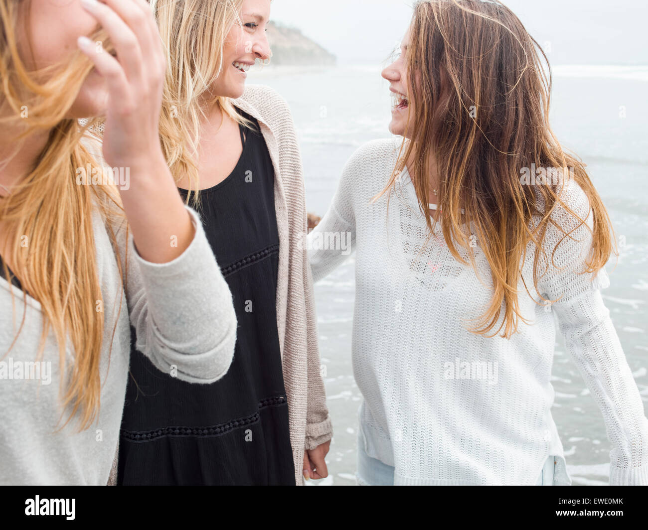 Three smiling young women walking on a beach Stock Photo