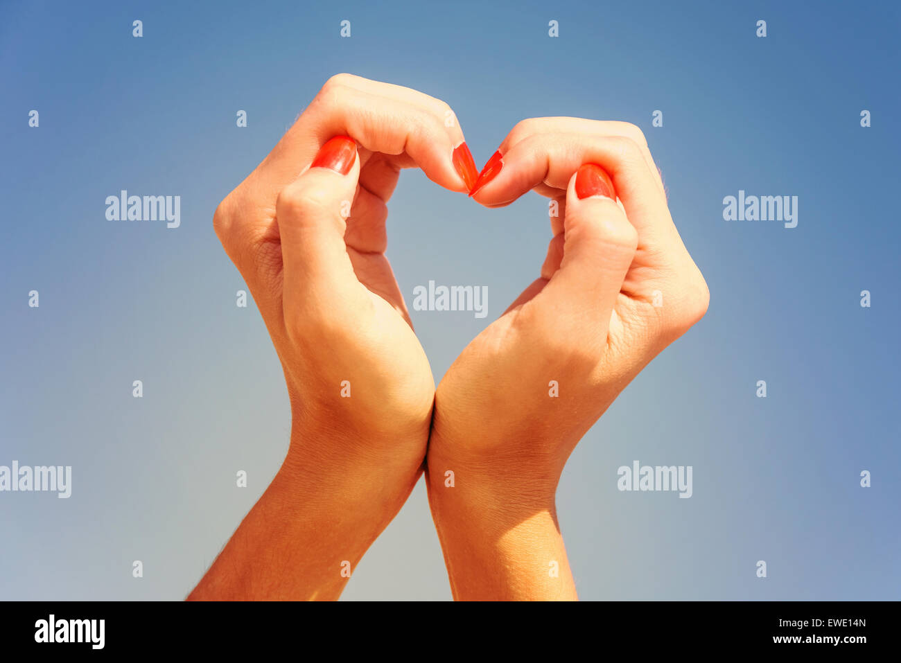 Retro Filter Of Girl Hands In Heart Shape On Blue Sky Stock Photo