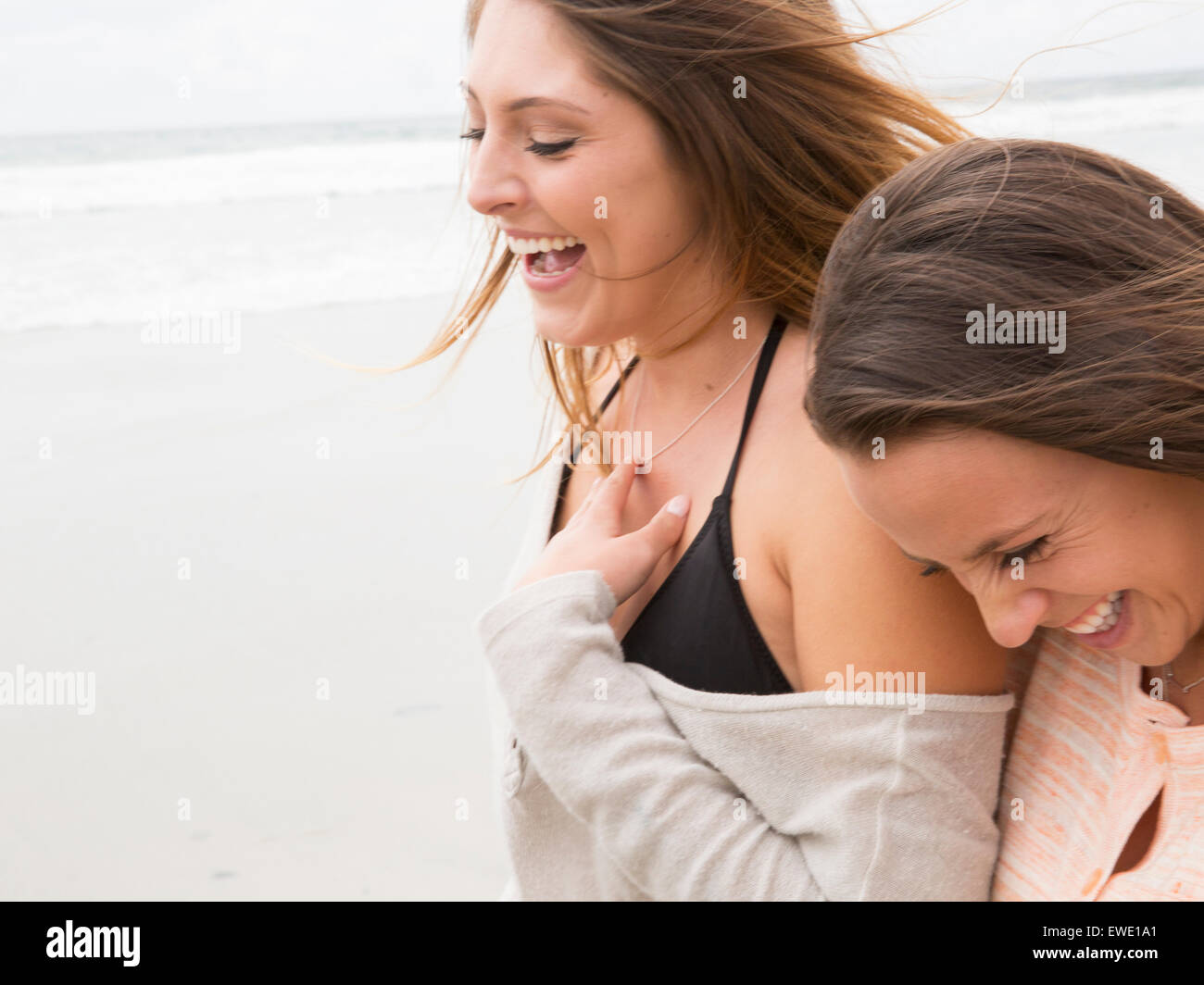 Close up of two smiling young women walking on a beach Stock Photo