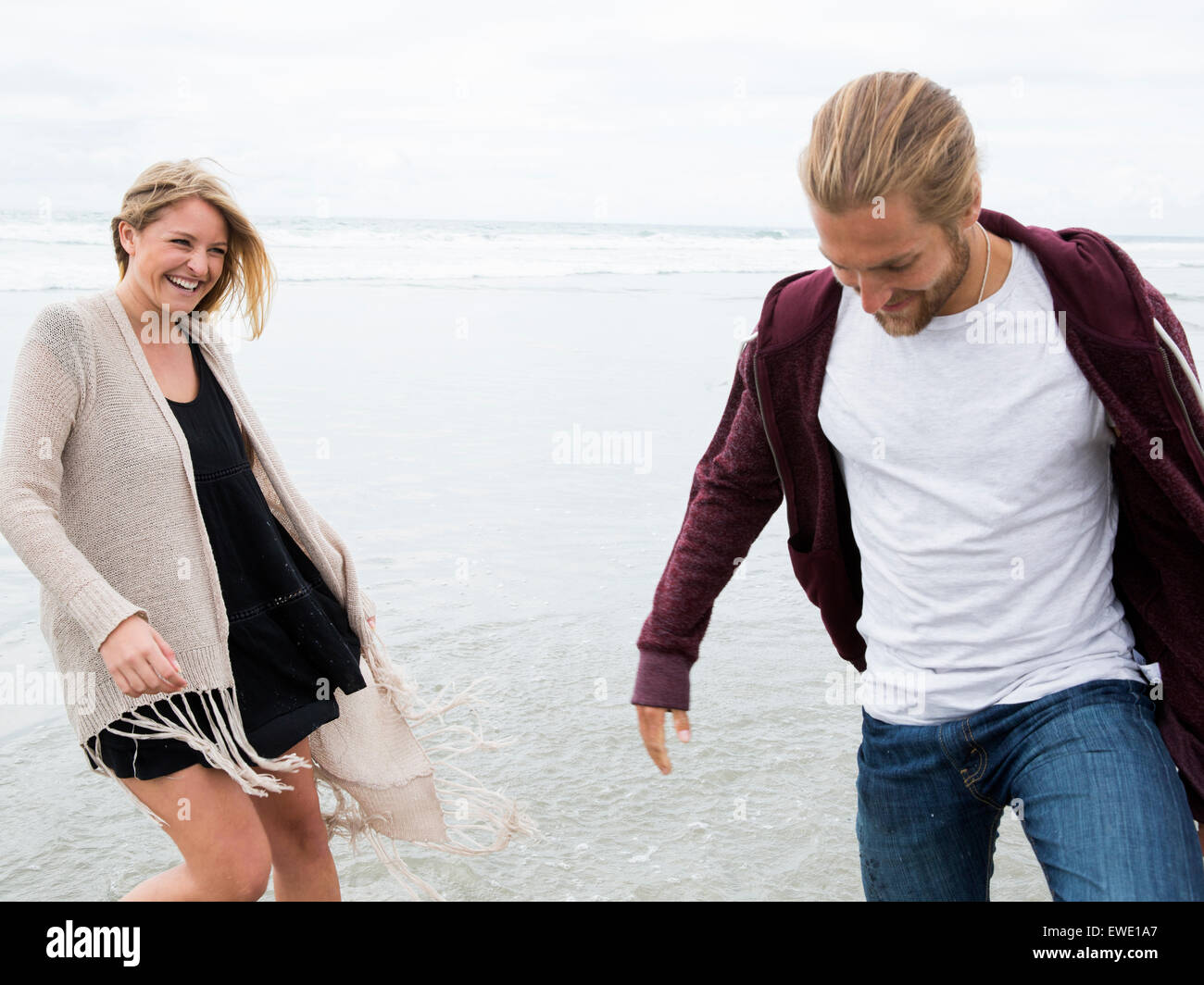 Young man and young woman walking on a beach, smiling Stock Photo