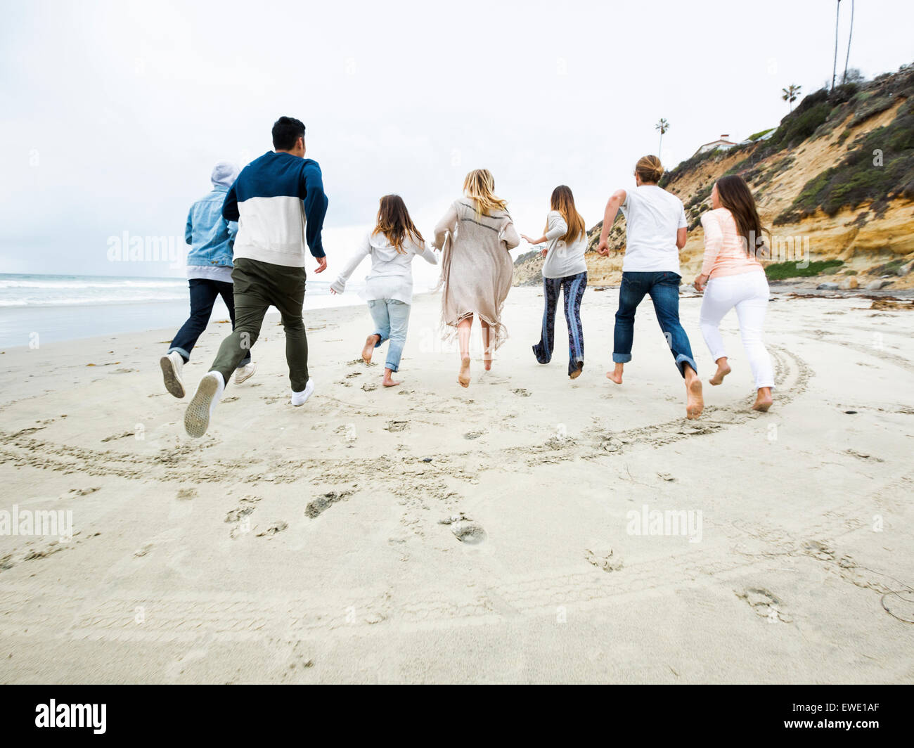 A group of young men and women running on a beach, having fun Stock Photo