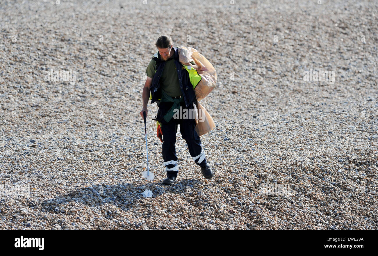 A Brighton and Hove City Council worker cleaning up litter on Brighton beach early morning Stock Photo
