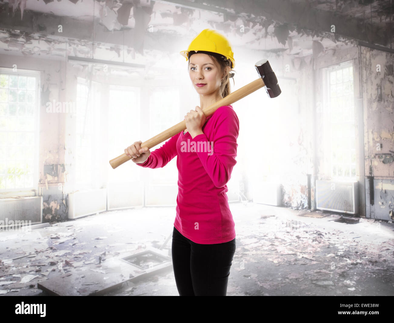 woman holding a sledgehammer and wearing a hard hat about to smash