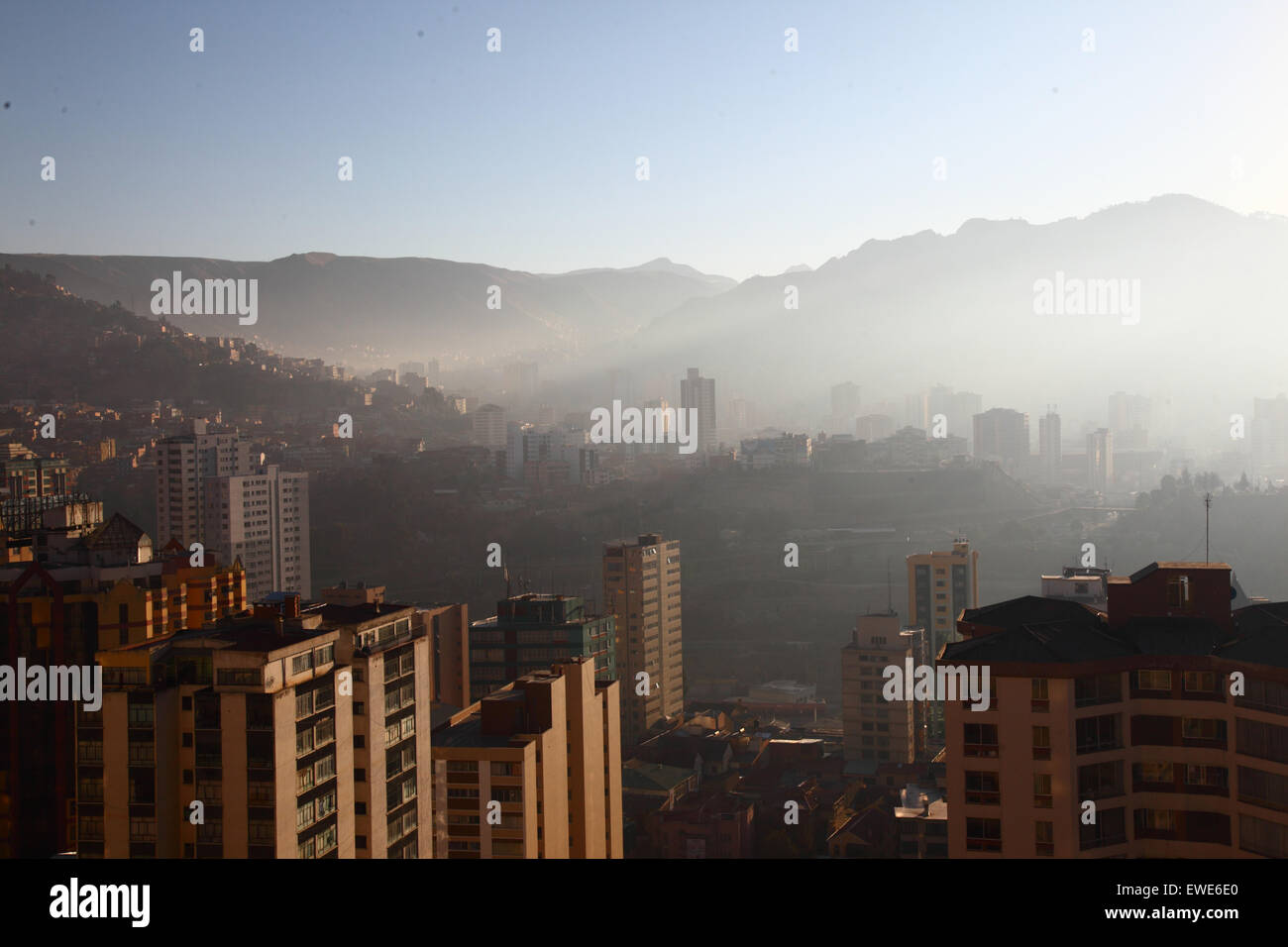 La Paz, Bolivia, 24th June 2015. Smoke fills the valleys of the centre of La Paz shortly after sunrise after San Juan night. San Juan is traditionally believed to be the coldest part of the year and many people in Bolivia light bonfires and set off fireworks. Local authorities have been attempting to stop this custom in the last few years to reduce the extra pollution it causes in the city, but with only limited success. This view looks east from Sopocachi to the Miraflores district  and the foothills of the Andes. Stock Photo