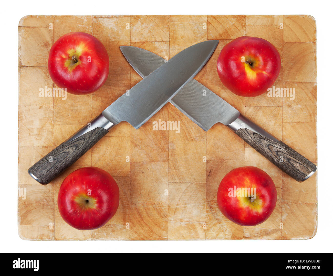Two Knives crossed on chopping board with four apples. Stock Photo