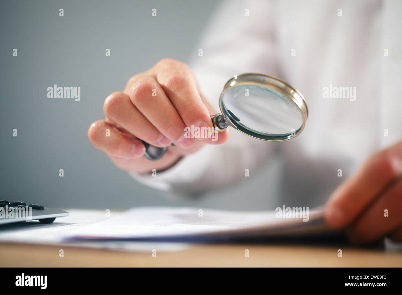 Businessman with magnifying glass reading documents Stock Photo