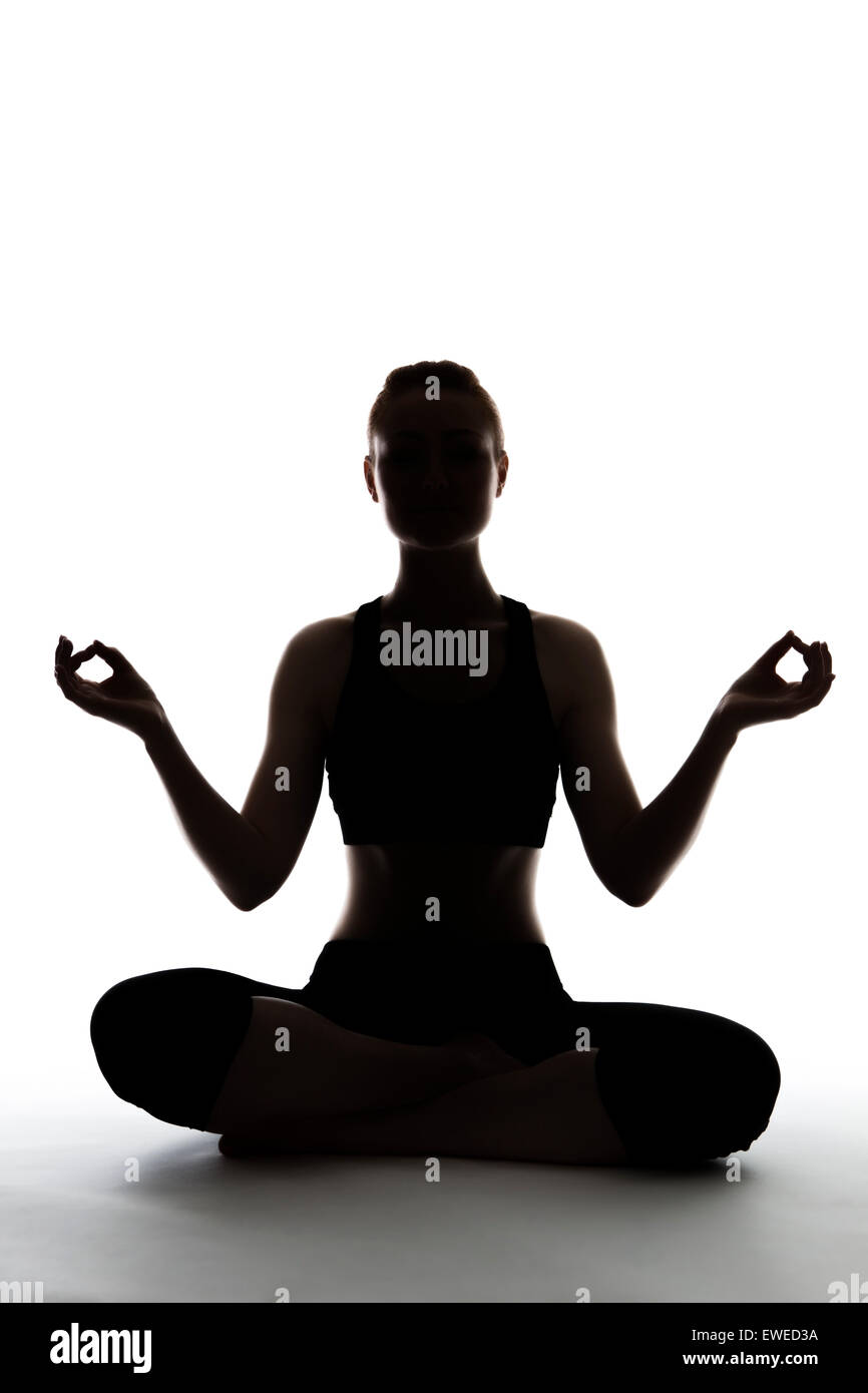 silhouette of young woman sitting on the floor doing yoga Stock Photo ...