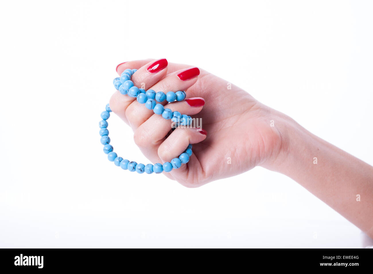Beautiful woman hands with red manicure holding color pearl necklace Stock Photo