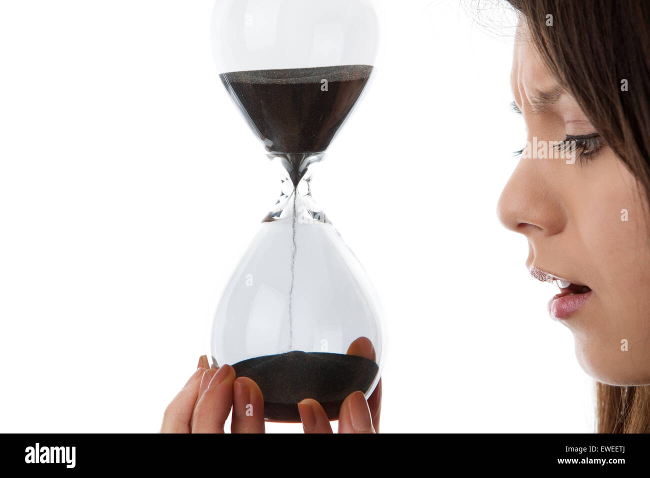woman holding up a hour glass sand timer watching time slip away Stock Photo