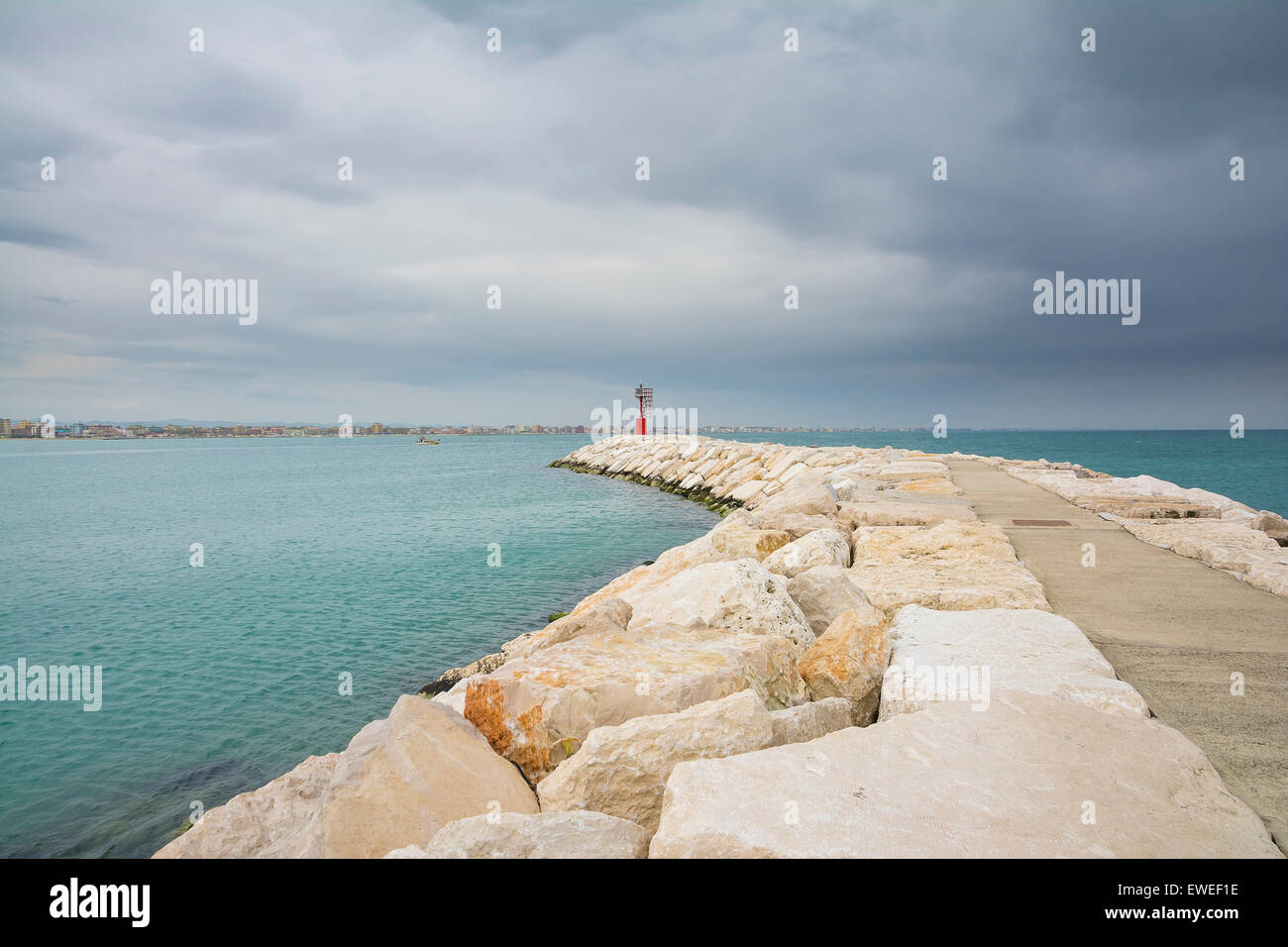 a red lighthouse  in front off the small port of Rimini during a cloudy day. Stock Photo