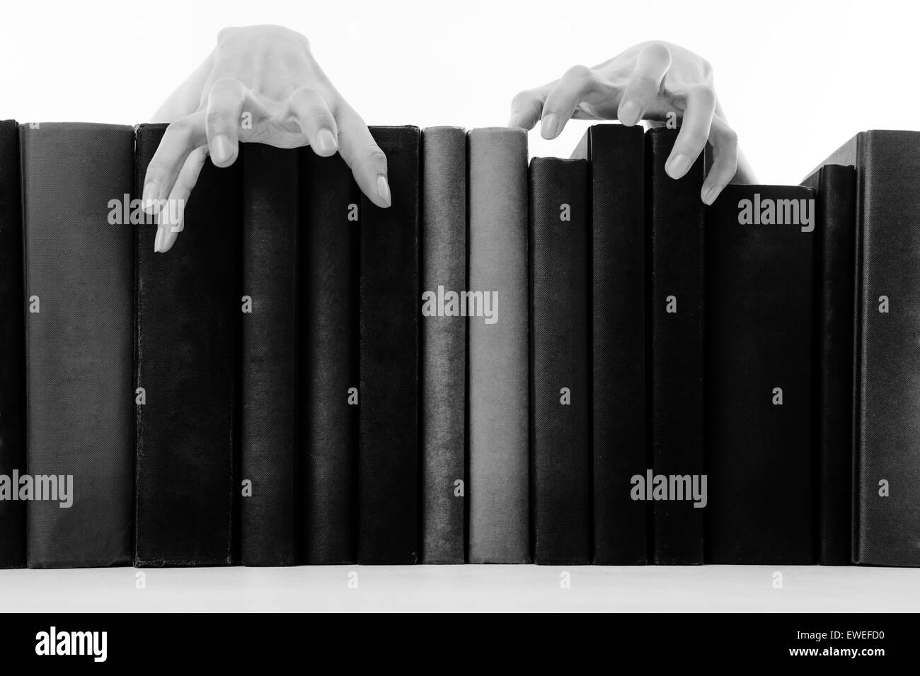 creepy hands coming over books on a bookshelf Stock Photo