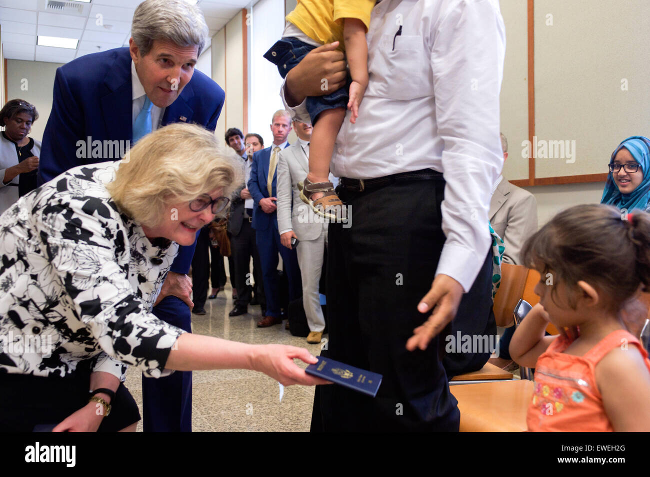 Acting Assistant Secretary of State for Consular Affairs Michele Bond, watched by U.S. Secretary of State John Kerry, hands travel papers to the daughter of a Yemeni-American whose family had to flee from Yemen during an event at the U.S. Embassy in Djibouti, Djibouti, on May 6, 2015, after the Secretary visited a local mosque, met with President Ismail Omar Guelleh and the Foreign Minister, and before a visit with U.S. forces at Camp Lemonnier. Stock Photo