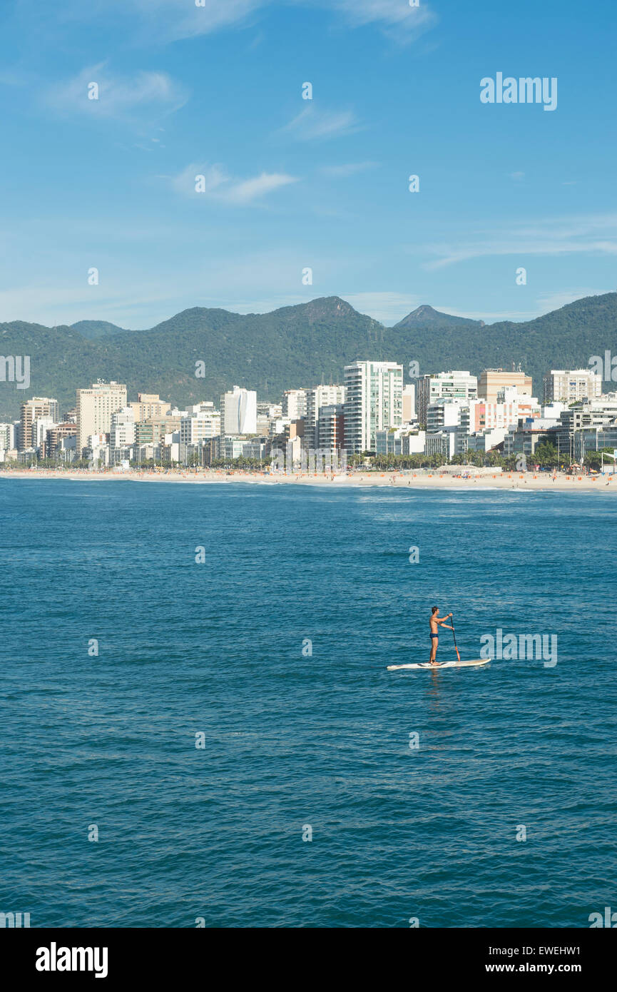 RIO DE JANEIRO, BRAZIL - MARCH 22, 2015: Brazilian stand up paddler enjoys calm seas near the Arpoador section of Ipanema Beach. Stock Photo