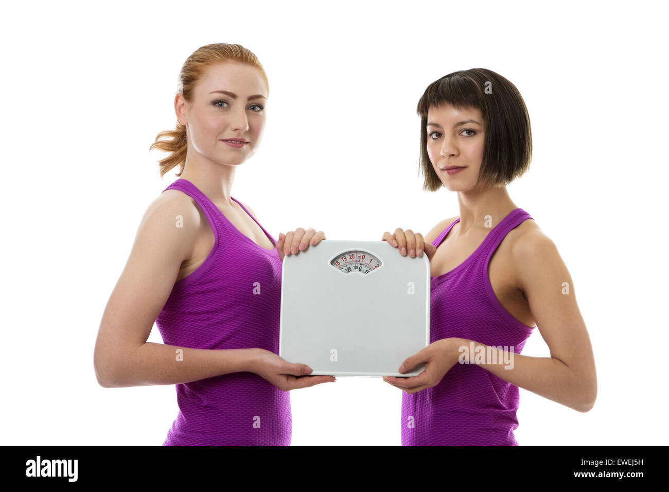 two fitness models holding scales between them Stock Photo
