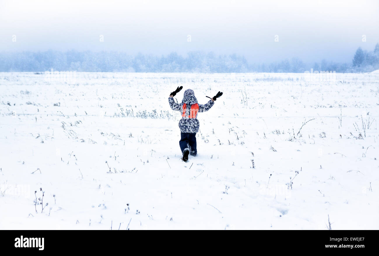 Little girl running  away on snow field Stock Photo