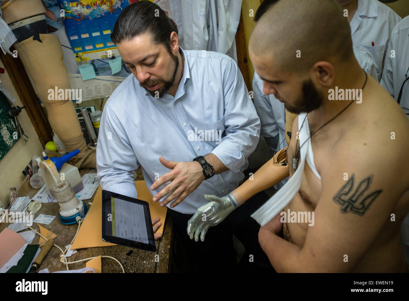 American prosthetist Chris Fantini shows how to use software ruling limb from tablet to Vasyl Pelysh, losted his hand in captivity at Donbas, when pro-Russian terrorists brutally cut it because of tattoo with Ukrainian national sign and phrase 'Honor to Ukraine'. Ukraine Prosthetic Assistance Project, charity project organized by Ukrainian and Canadian medical workers and public figures to transfer prosthetic and rehabilitation knowledge from American and Canadian specialists to their colleagues in Ukraine. During project five Ukrainians received high quality bionic prosthesis, including three Stock Photo