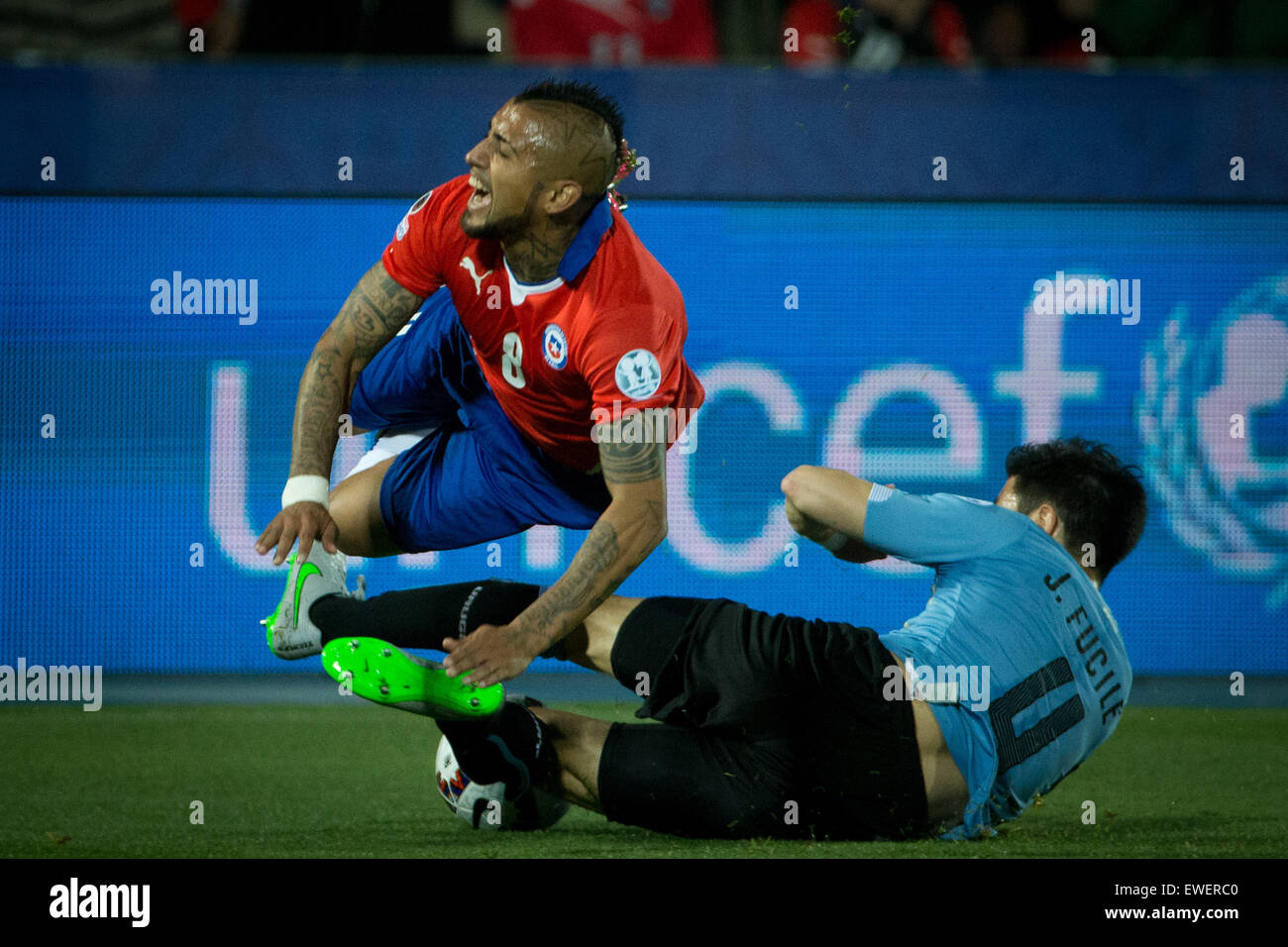 Santiago, Chile. 24th June, 2015. Arturo Vidal (Top) of Chile is tackled by Jorge Fucile of Uruguay during their quarterfinal at 2015 Copa America in Santiago, Chile, on June 24, 2015. Credit:  Pedro Mera/Xinhua/Alamy Live News Stock Photo