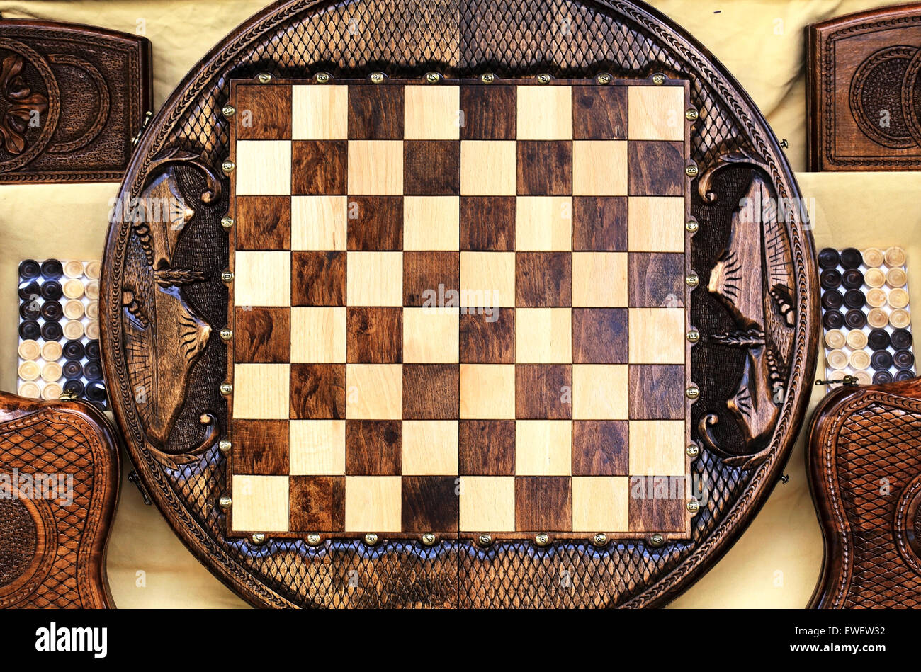 Checkerboard of the round shape made of wood and decorated with carvings Stock Photo