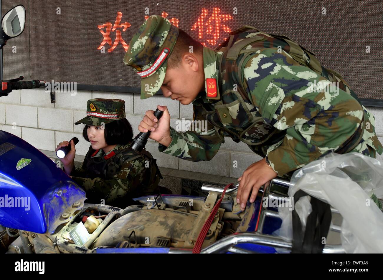 (150625) -- DEHONG, June 25, 2015 (Xinhua) -- Zhang Liu (L) and her comrade check a refitted motorcycle for contraband at the border checkpoint of Mukang in Dehong Dai-Jingpo Autonomous Prefecture, southwest China's Yunnan Province, June 24, 2015. Born in 1995, Zhang Liu became an anti-drug soldier in border checkpoint of Mukang in 2013.  Grown up in an affluent family in central China's Hunan Province, Zhang said that being a soldier had always been her dream, which drove her to join the army after graduating from high school. Being a front line anti-drug force, the border checkpoint of Mukan Stock Photo