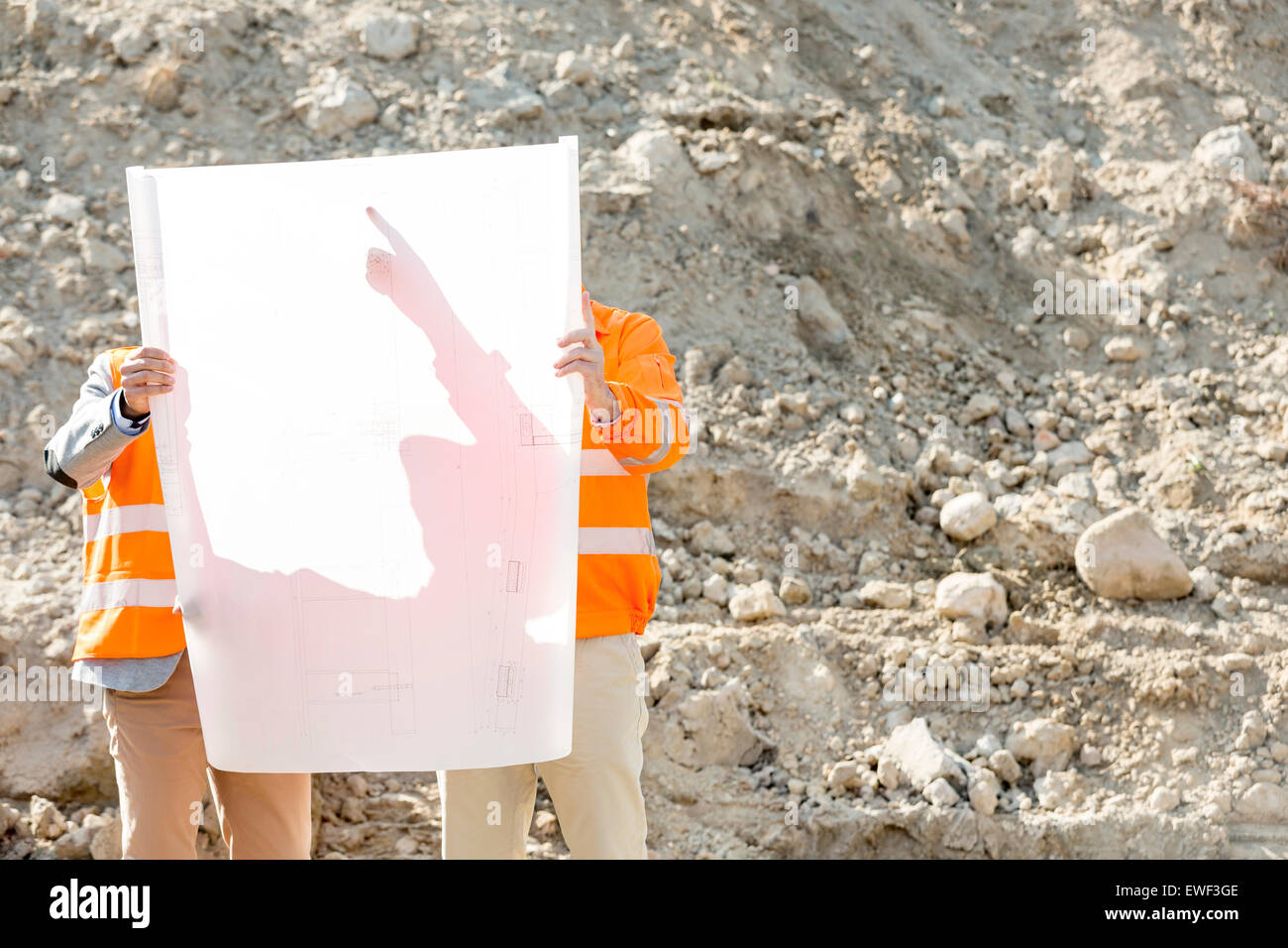 Engineers examining blueprint at construction site Stock Photo