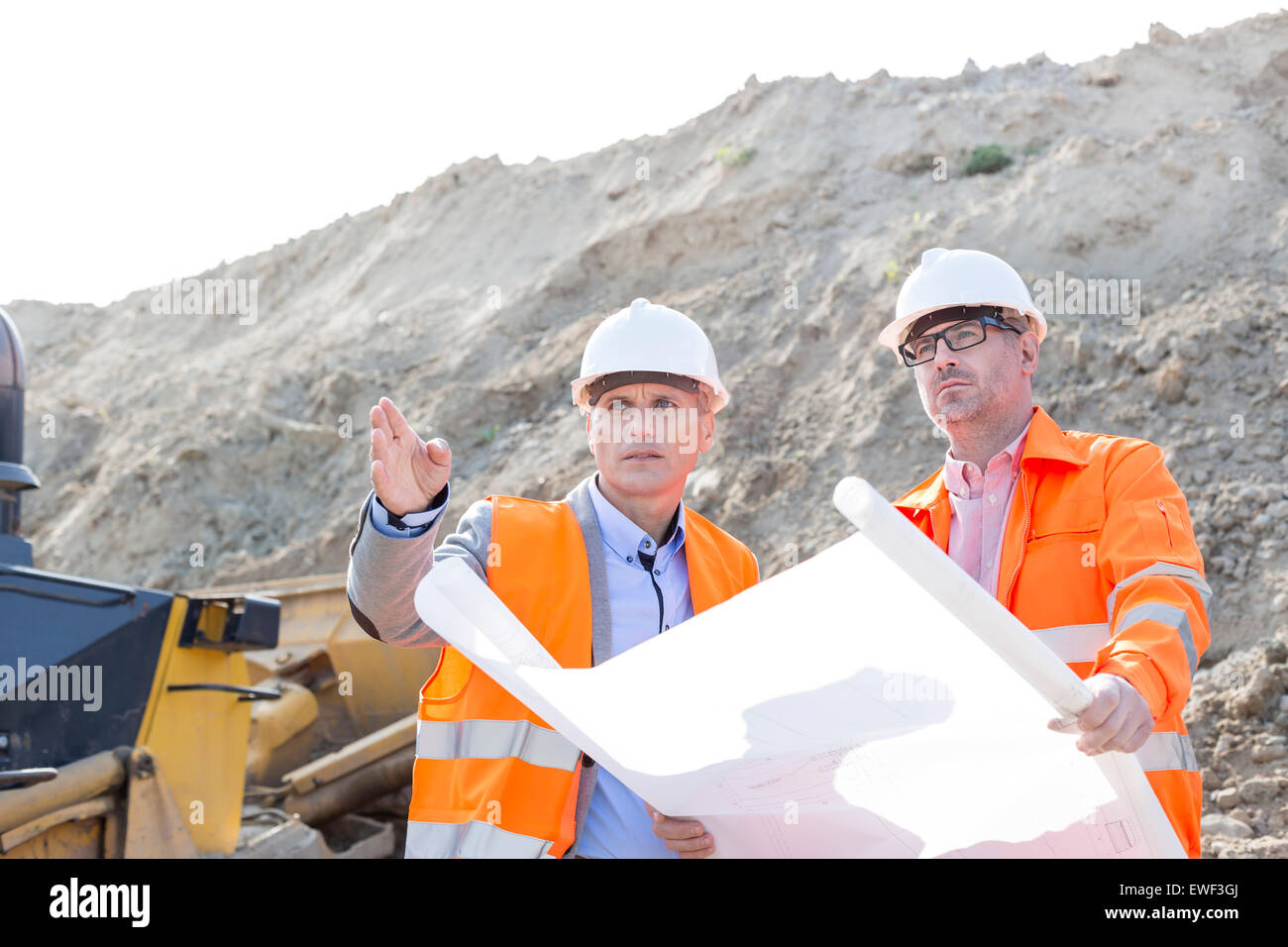 Engineers discussing over blueprint at construction site Stock Photo