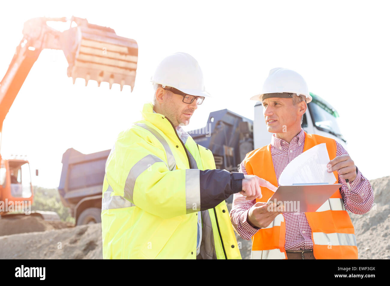 Engineers discussing over documents at construction site Stock Photo