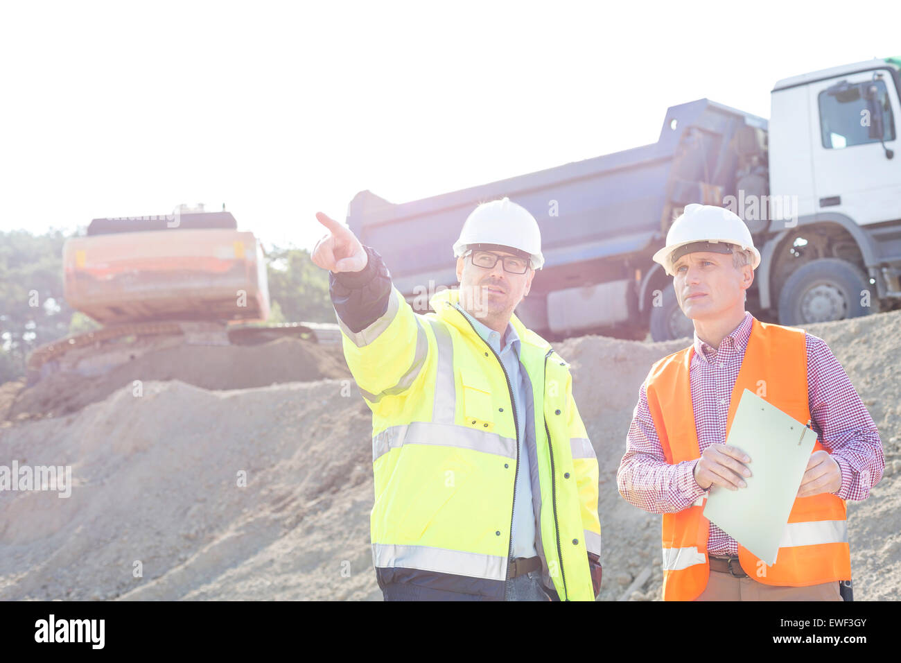 Supervisor showing something to colleague while discussing at construction site Stock Photo